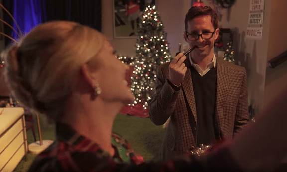 david adams with a pipe in his mouth in front of a christmas tree