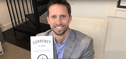 david adams holding a copy of his currency of time book